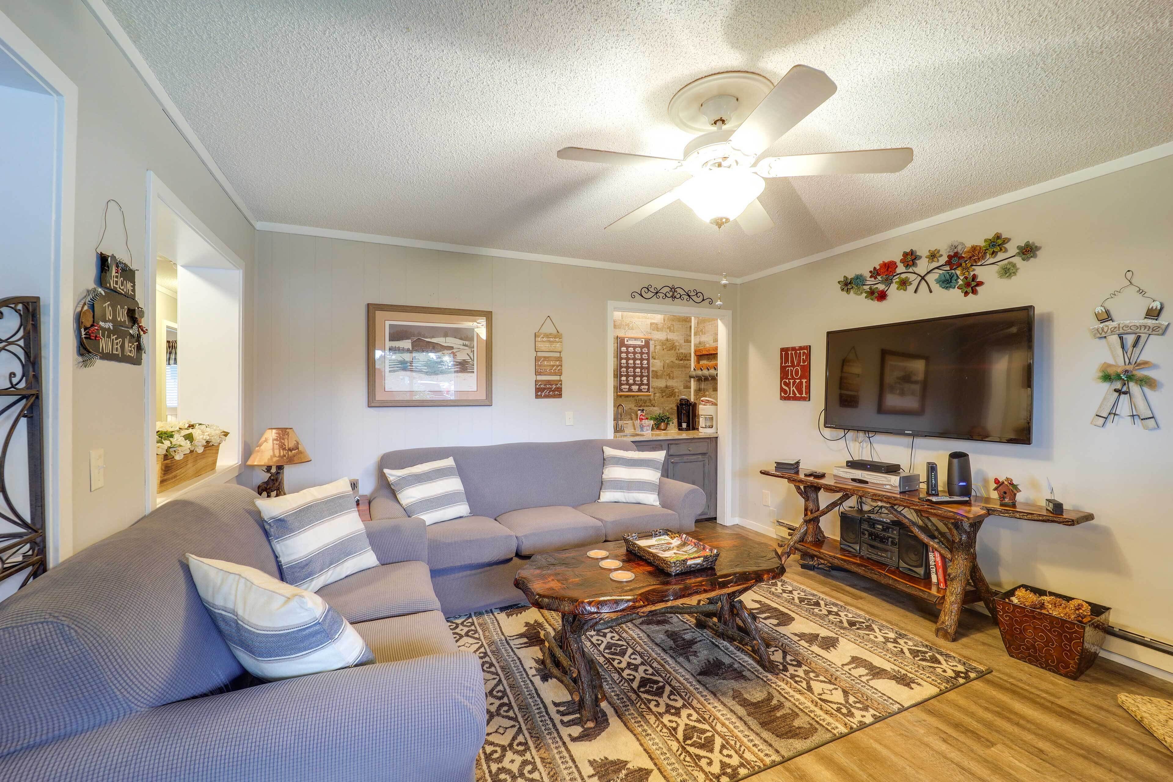 A living room with a gray sofa, a coffee table, a TV, and a ceiling fan.