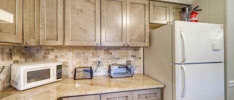 Una cocina con armarios de madera, un microondas, un tostador y un refrigerador.