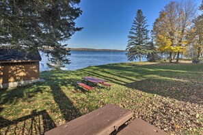 A lakeside view with picnic tables and a building. - Cozy Cabin w/ Deck & Private Dock on Nelson Lake! (Hayward)