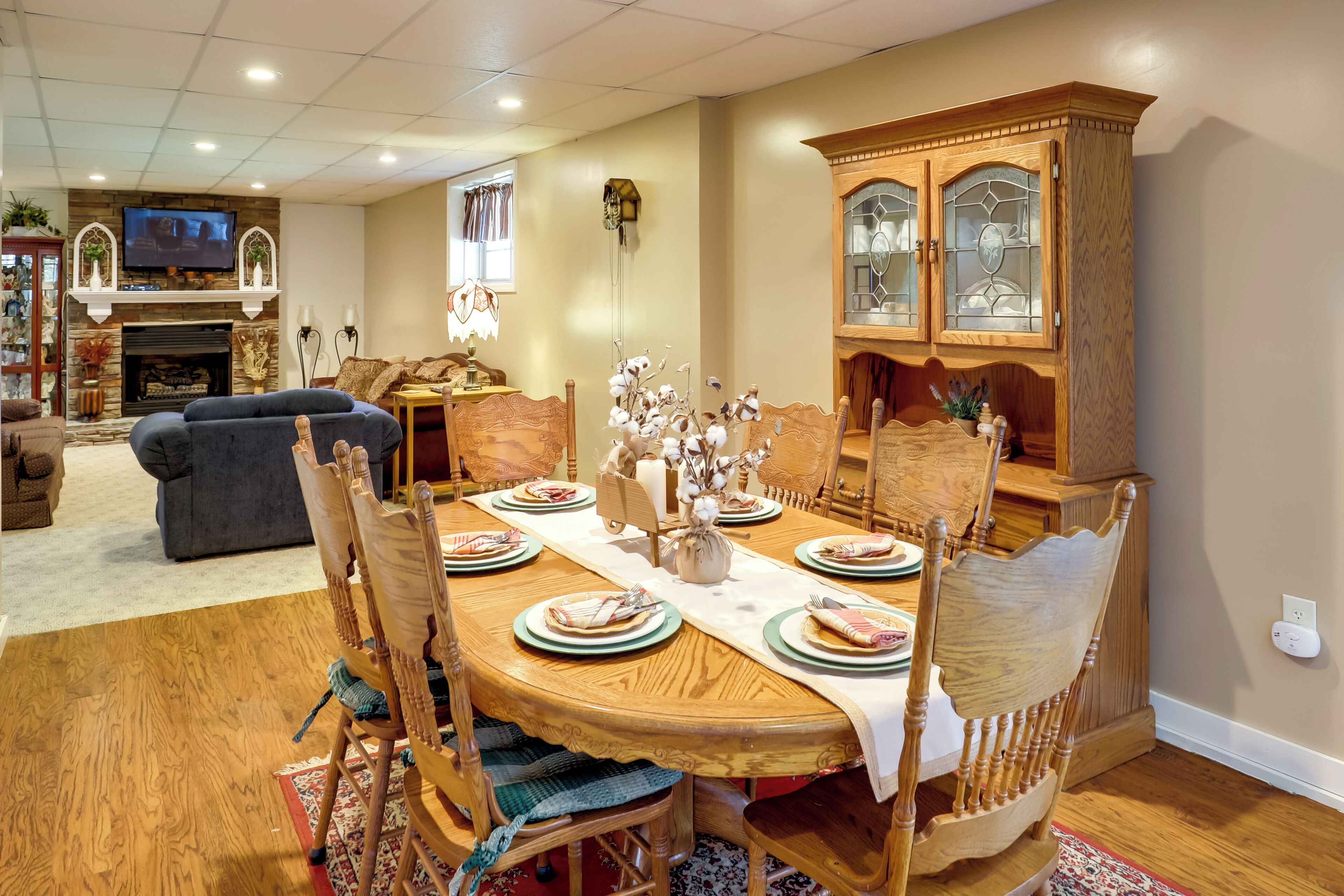 Une salle à manger avec une table en bois dressée pour quatre personnes, entourée de chaises en bois.