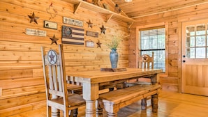 A wooden interior with a wooden table, benches, and a clock on a chair. - Cozy New Braunfels Family Cabin w/ Porch & Views! (New Braunfels)