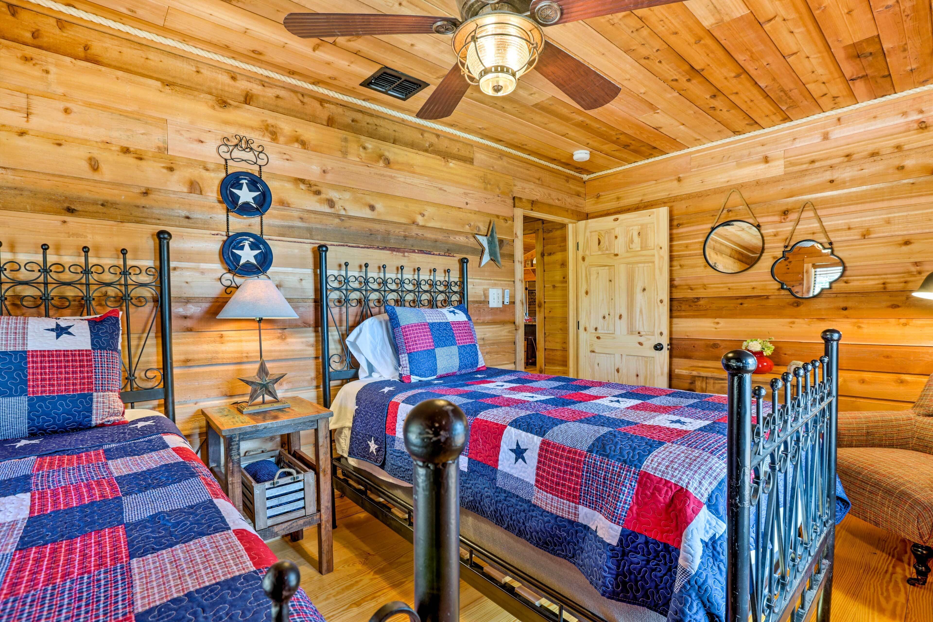 Ein Schlafzimmer einer Holzhütte mit zwei Betten, einem Deckenventilator und einer gesteppten Bettdecke.