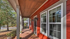 Ein rotes Holzhaus mit Veranda, großen Fenstern und einer sichtbaren Tür.
