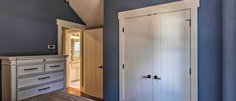 A bedroom with a bed, a dresser, a ceiling fan, and a white door.