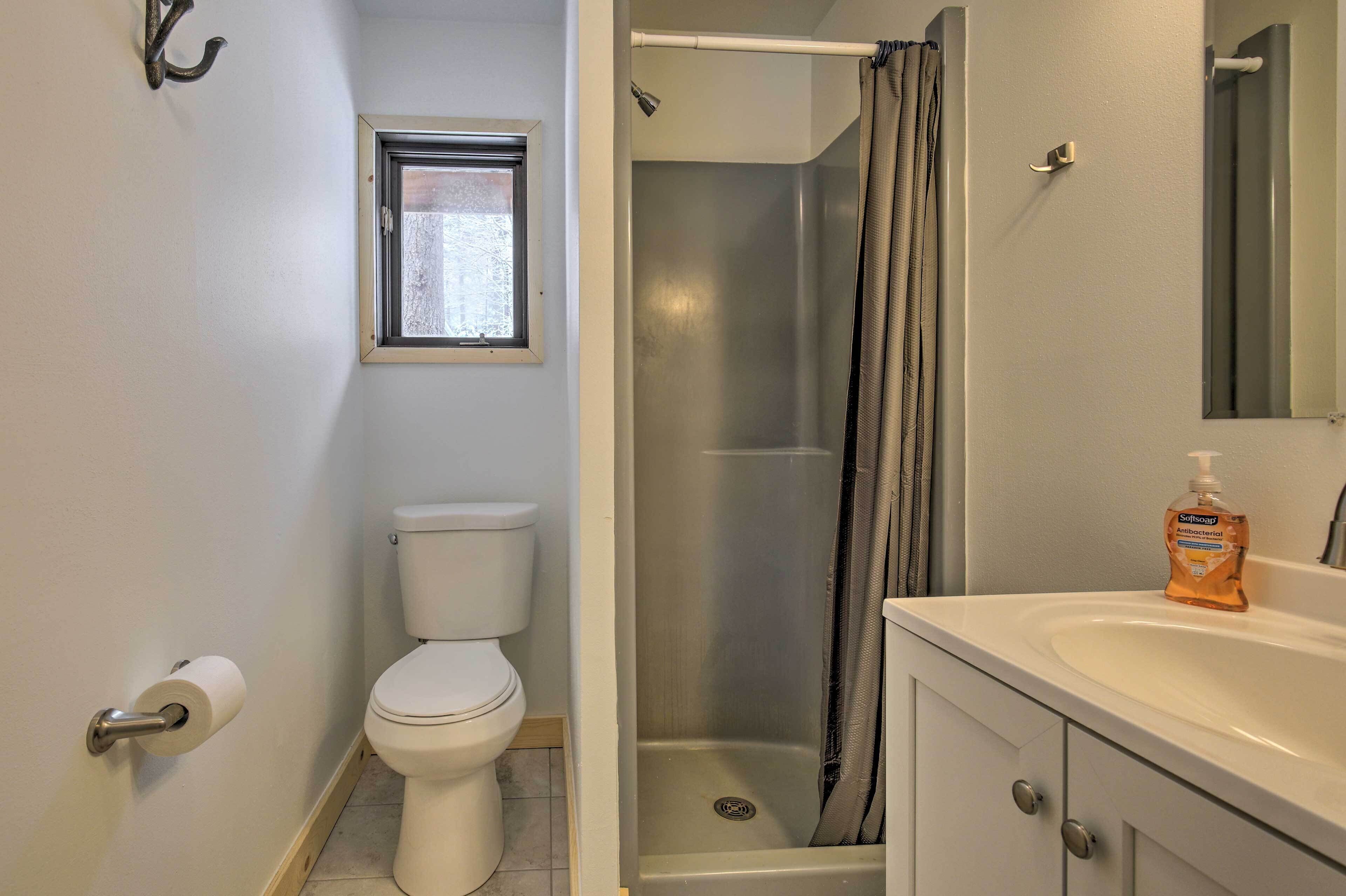 A bathroom with a toilet, a shower, a sink, and a window.