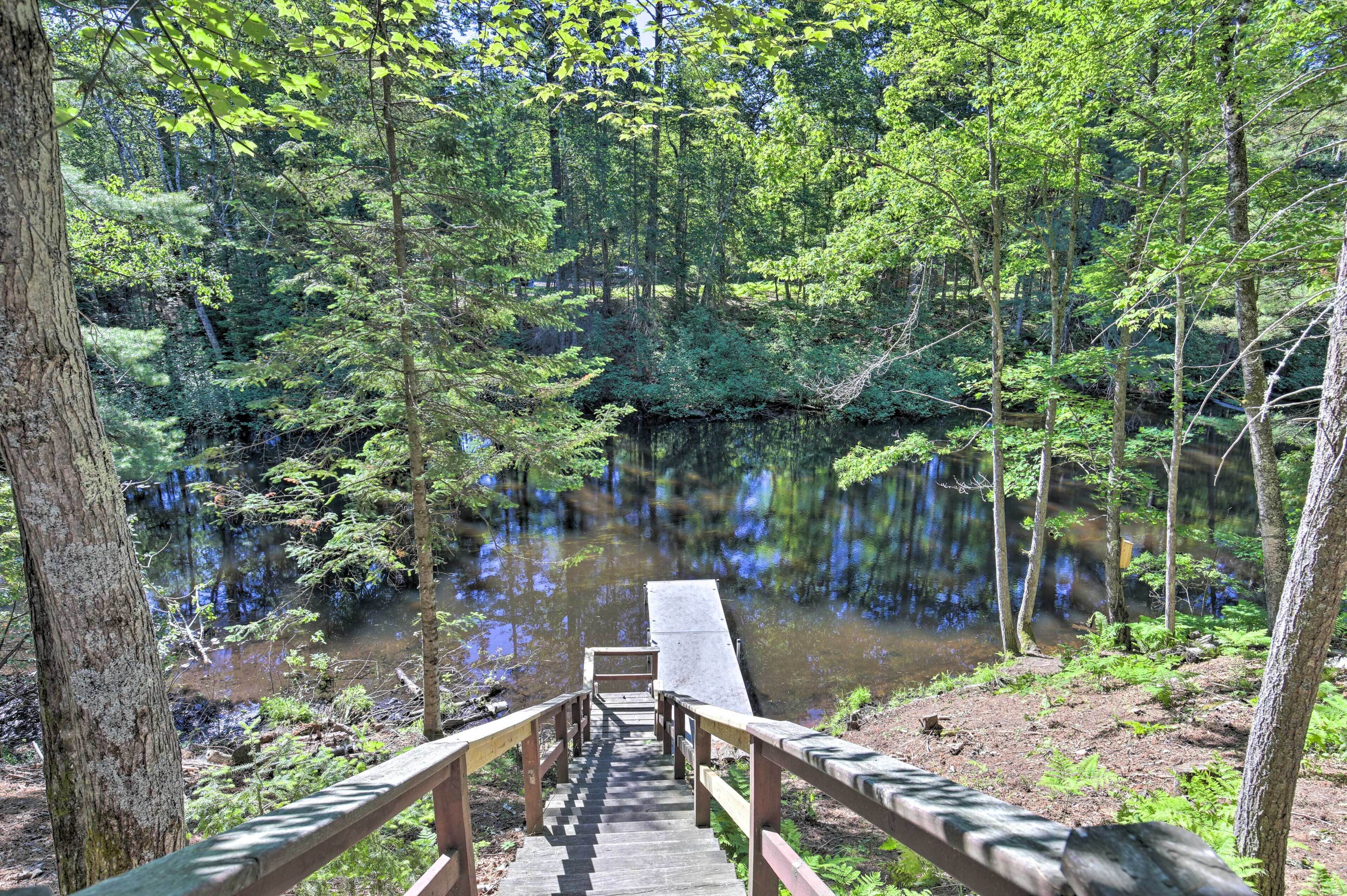 Eine Holzterrasse führt zu einem ruhigen See, der von dichtem Wald umgeben ist.