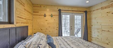 A wooden-paneled bedroom with a bed, a window, and a door leading to a balcony.