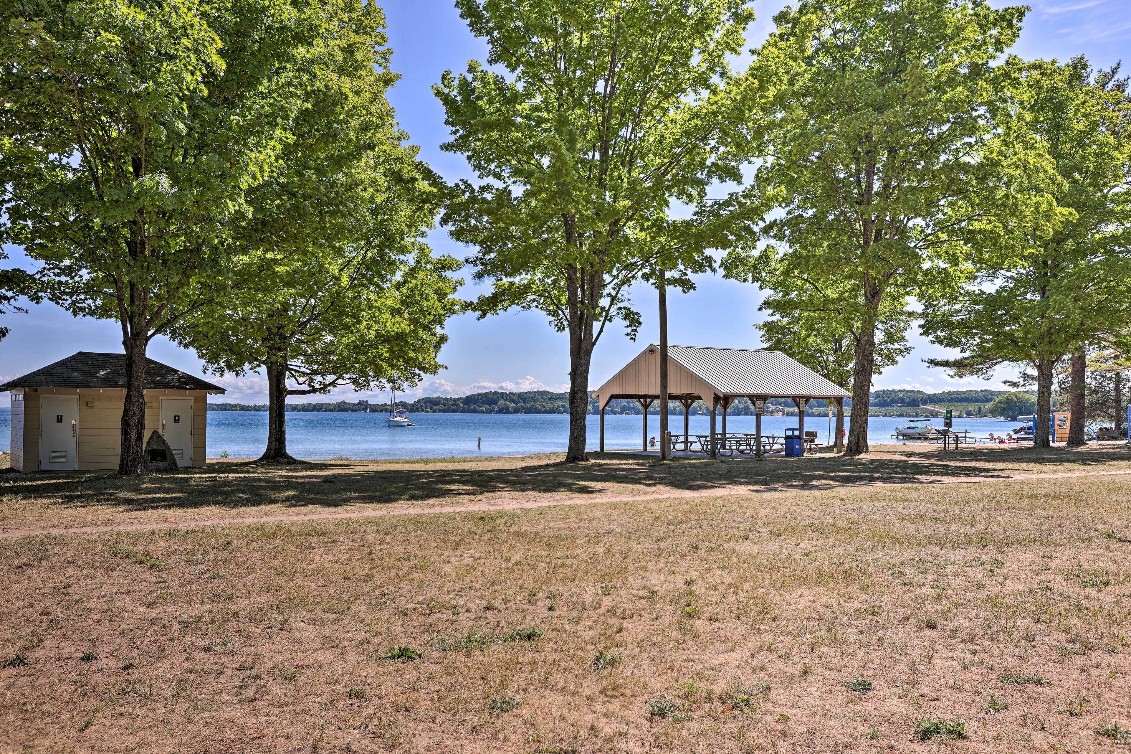 A lakeside park with picnic tables, a small shelter, and a cabin.
