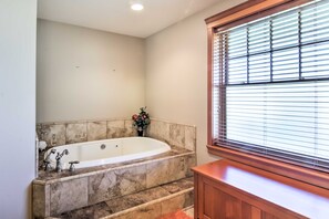 A bathroom with a freestanding bathtub, marble tiles, a wooden bench, and a window with blinds. - Custom Home w/ Decks in Boulder! Gateway to Parks! (Boulder)