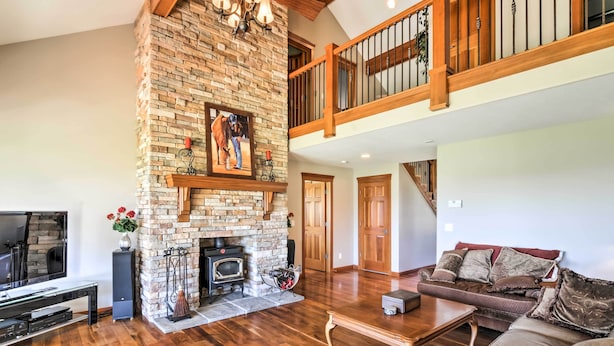 A spacious living room with a stone fireplace, wooden flooring, a large leather sofa, and a TV. - Custom Home w/ Decks in Boulder! Gateway to Parks! (Boulder)