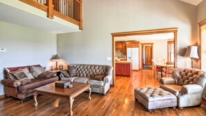 A spacious living room with a sectional sofa, a leather armchair, and a wooden coffee table. A kitchen is visible in the background. - Custom Home w/ Decks in Boulder! Gateway to Parks! (Boulder)