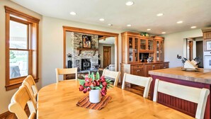 A dining area with a wooden table, chairs, and a vase of flowers. There is a kitchen area with wooden cabinets and a fireplace in the background. - Custom Home w/ Decks in Boulder! Gateway to Parks! (Boulder)