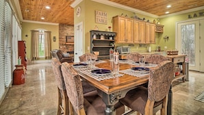A dining area with a wooden table set for six, surrounded by patterned chairs. - Dog-friendly Family Home Steps to Norris Lake (Sharps Chapel)