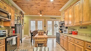 A kitchen with wooden cabinets, a central island, and a stainless steel trash can. - Dog-friendly Family Home Steps to Norris Lake (Sharps Chapel)