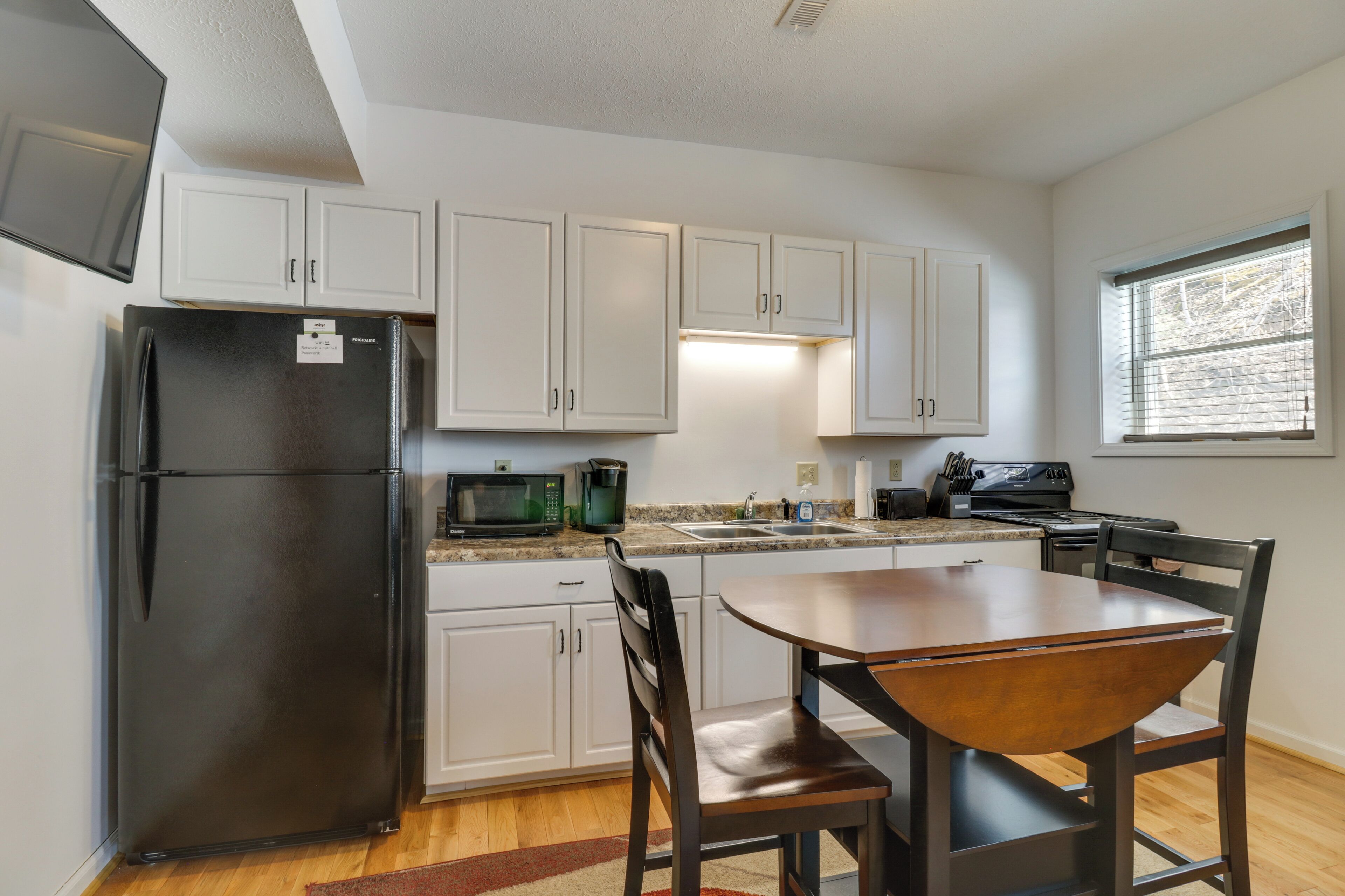 A modern kitchen with white cabinets, a black refrigerator, a microwave, and a stove.