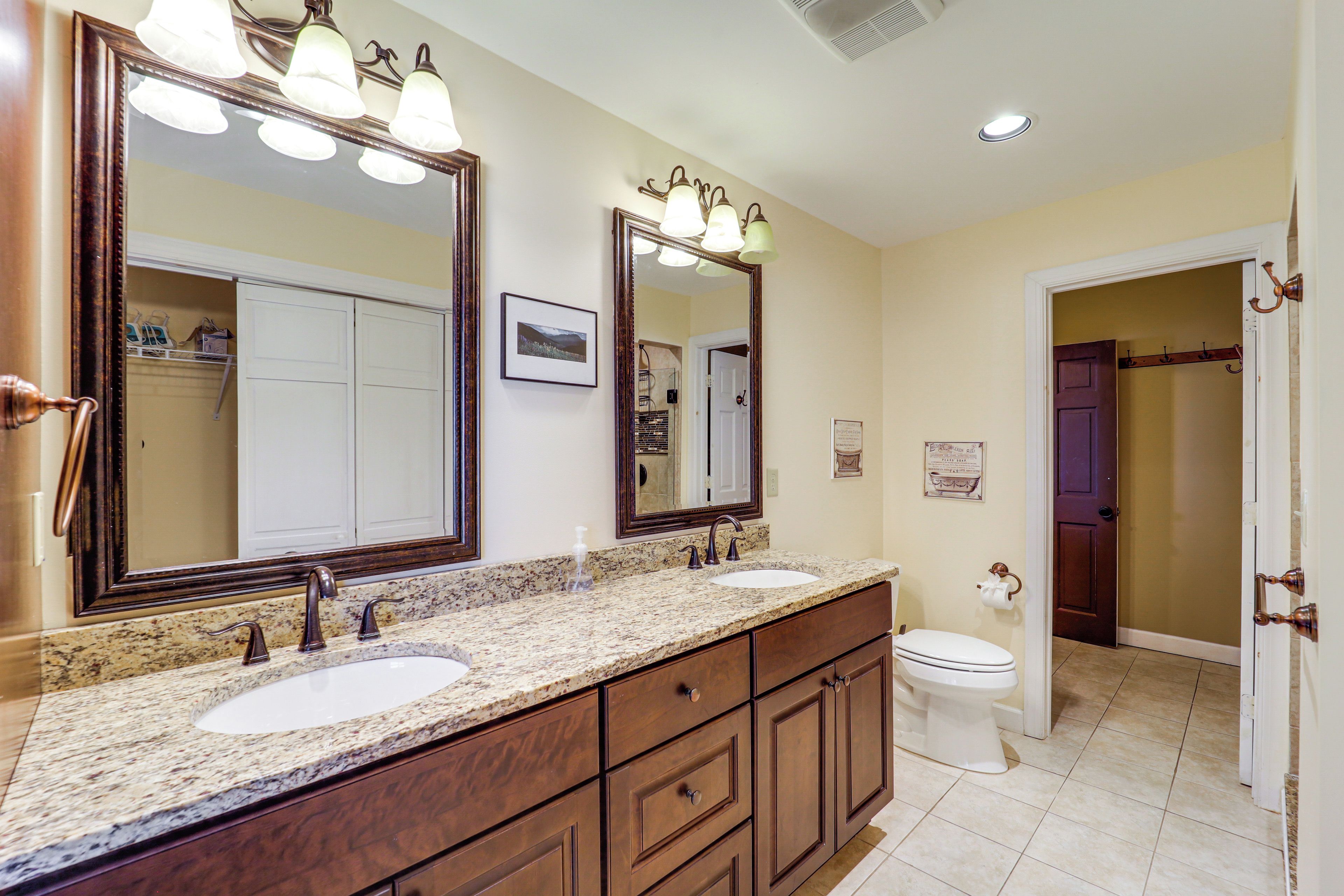 A bathroom with two sinks, a large mirror, and a toilet.