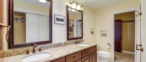 A bathroom with two sinks, a large mirror, and a toilet.