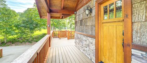 A wooden deck with a stone wall and a wooden door.