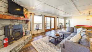 Ein Wohnzimmer mit Kamin aus Stein, einem flachbildfernseher darüber, einem Billardtisch und einem Ecksofa.