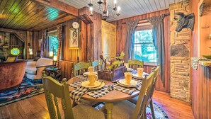 Un comedor rústico con paredes de madera, una araña y una chimenea de piedra.