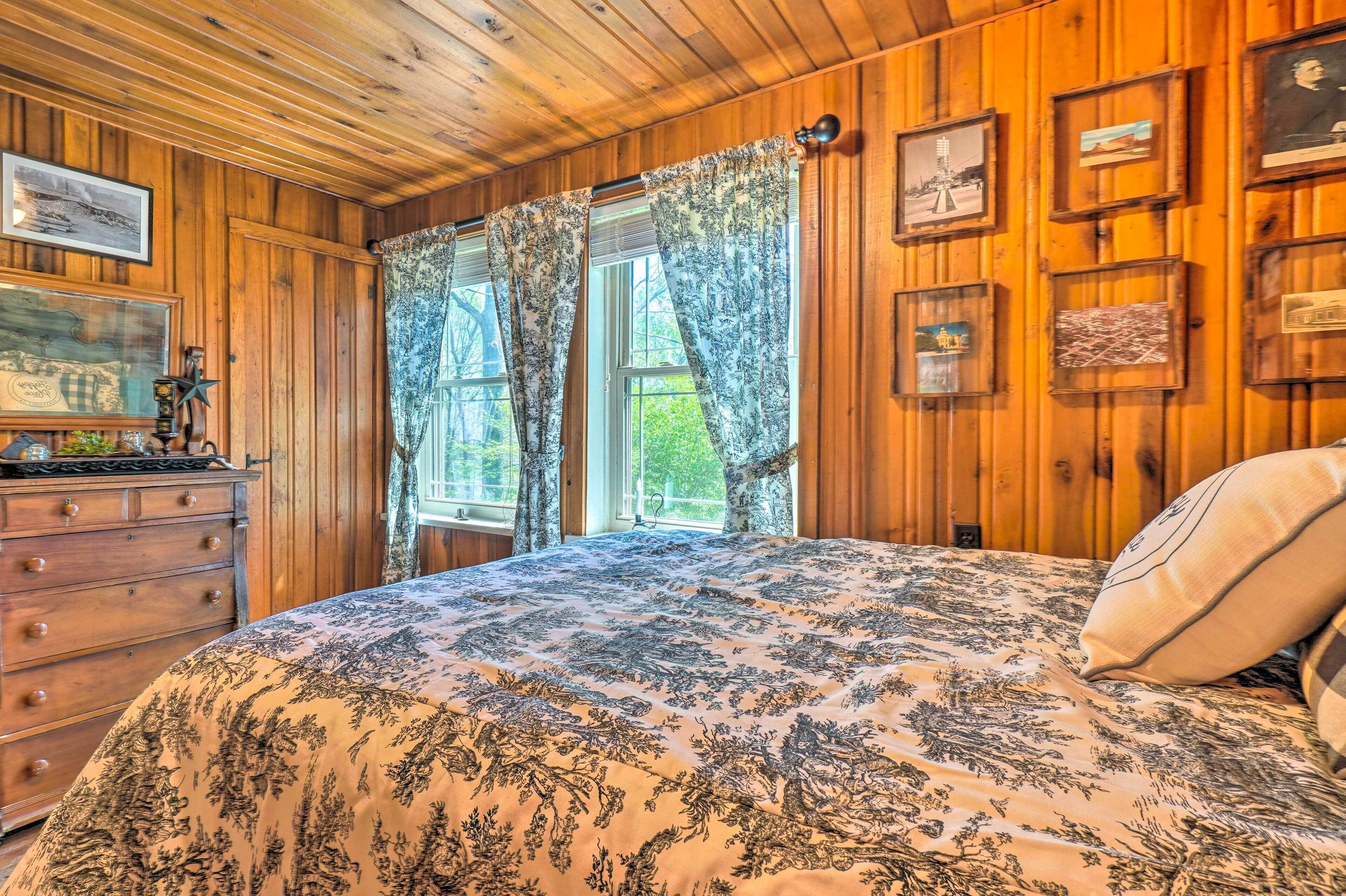 Een slaapkamer in een houten chalet met een bed, een dressoir en ingelijste foto's aan de wand.