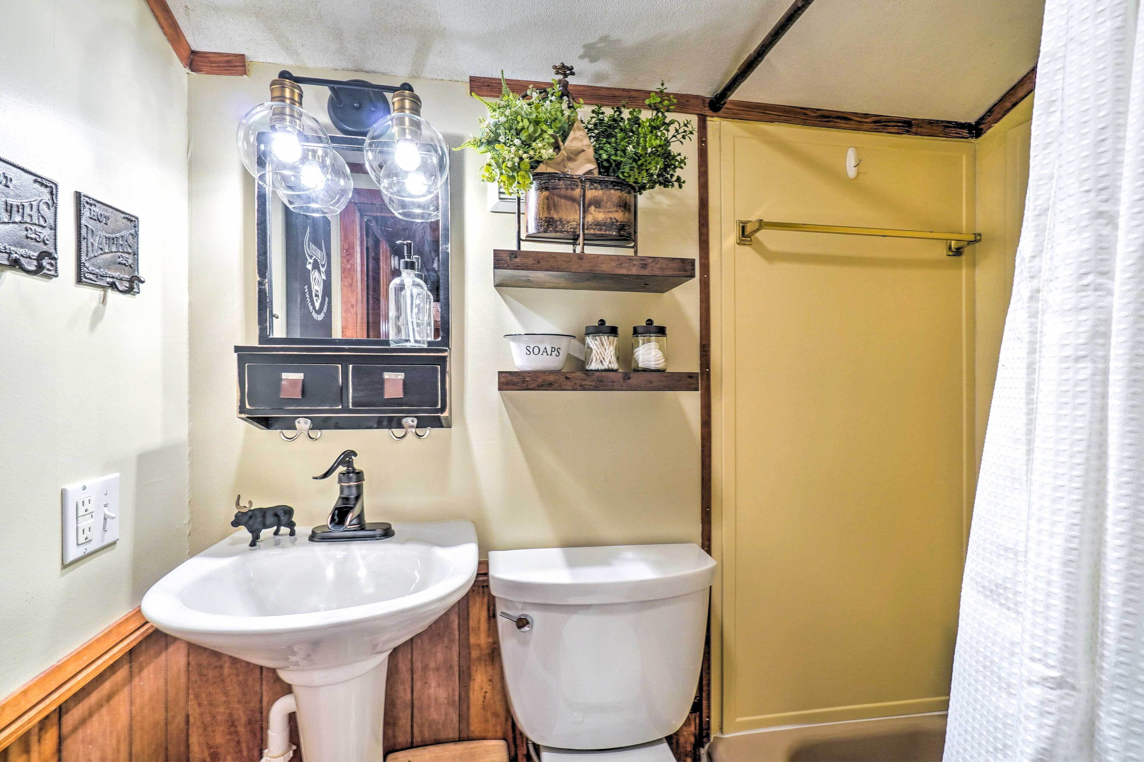 A bathroom with a white sink, toilet, and shelves with toiletries.
