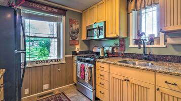 A kitchen with wooden cabinets, a stainless steel refrigerator, a microwave, and a stove.