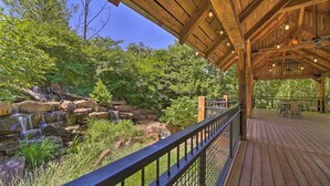 A wooden deck with a railing overlooking a natural landscape with a waterfall and greenery. - Falling Water Chalet Upper Unit: Near Bike Trails! (Bella Vista)
