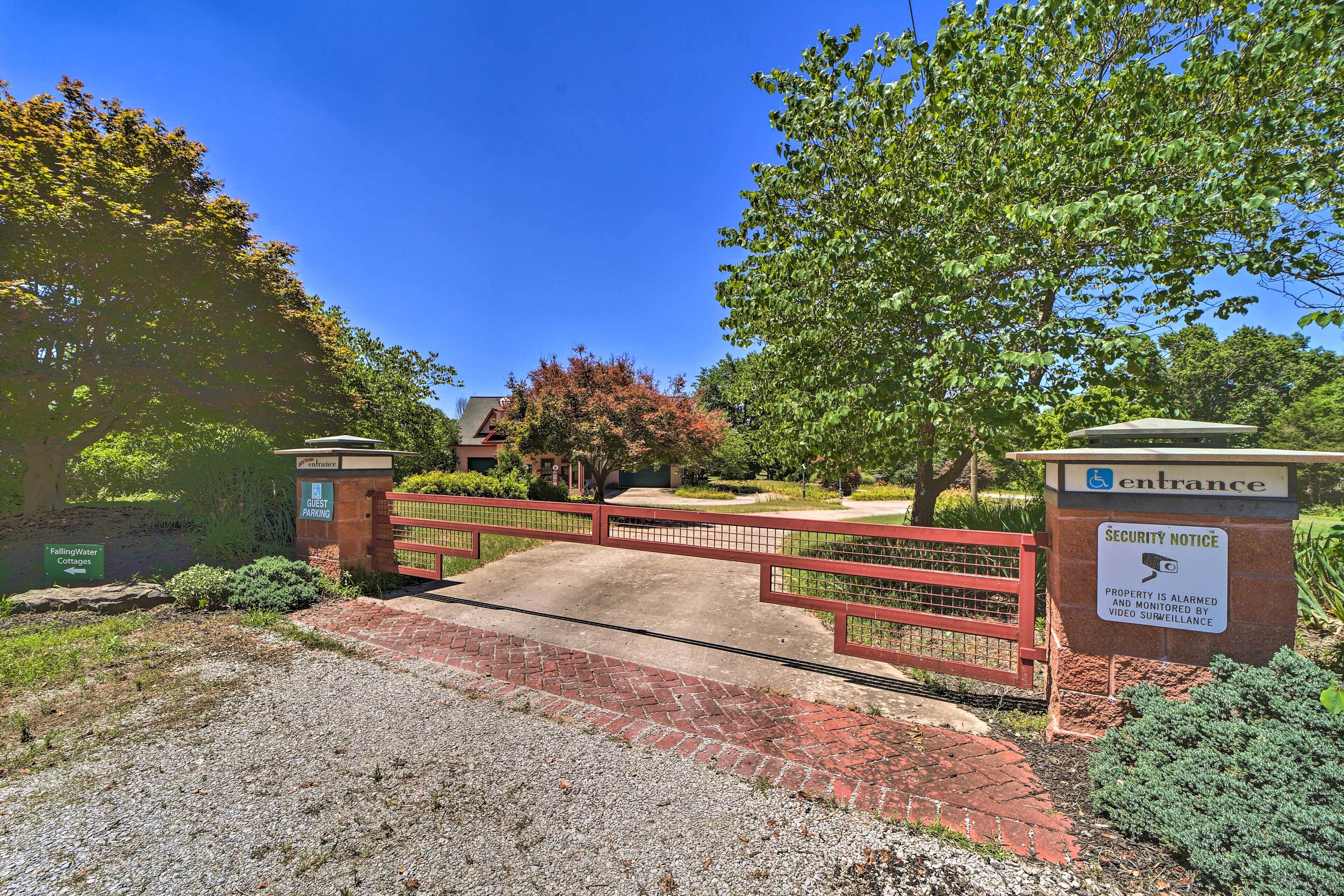 A gated entrance with a security notice sign, a brick pathway, and a building in the background.