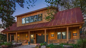 A two-story wooden house with a metal roof, large windows, and a front porch. - Falling Water Chalet Upper Unit: Near Bike Trails! (Bella Vista)