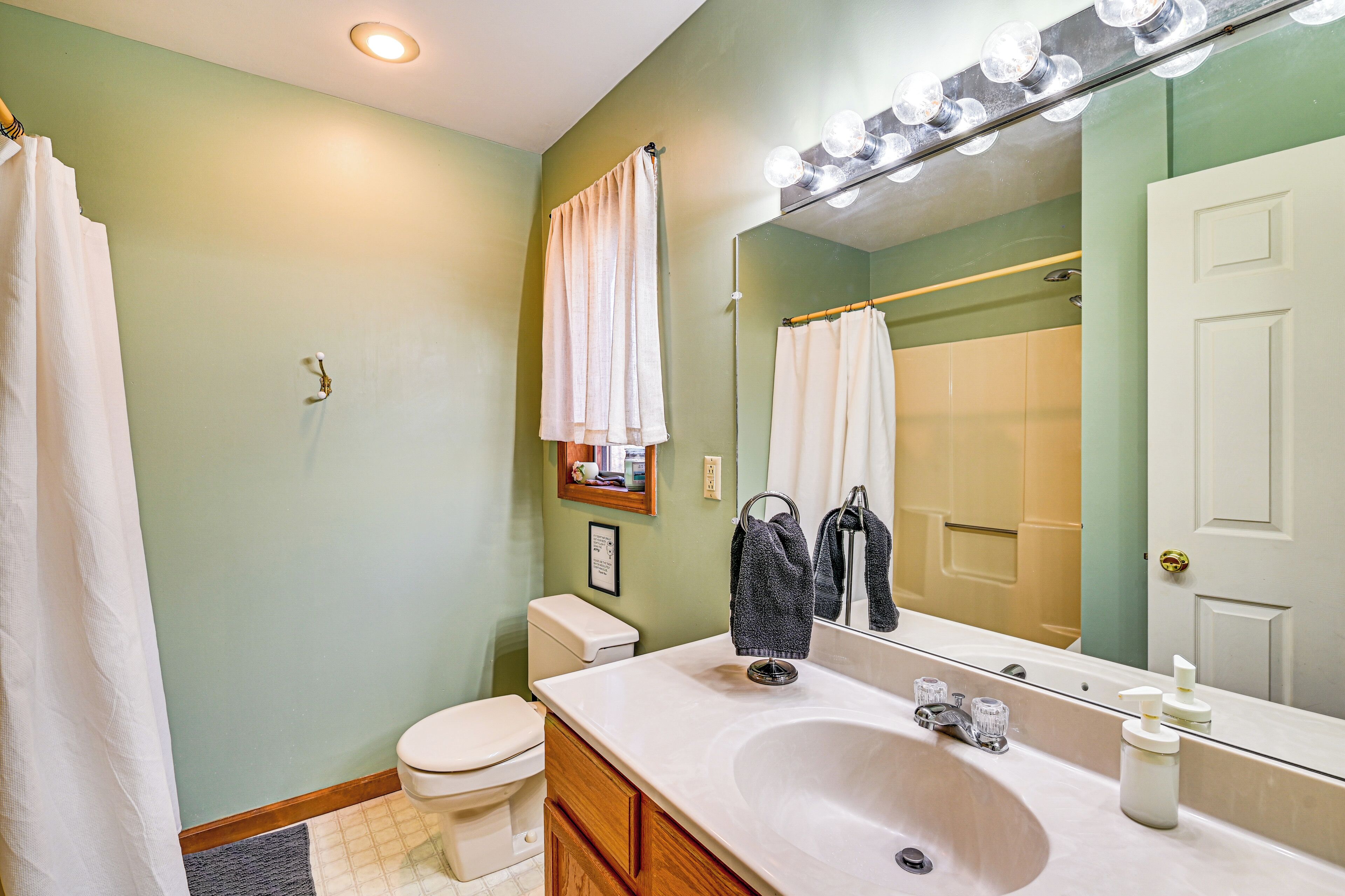 A bathroom with a sink, mirror, and lights above the mirror.