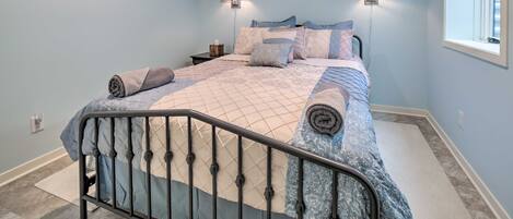 A bedroom with a bed, two wall-mounted lamps, a nightstand, and a window.
