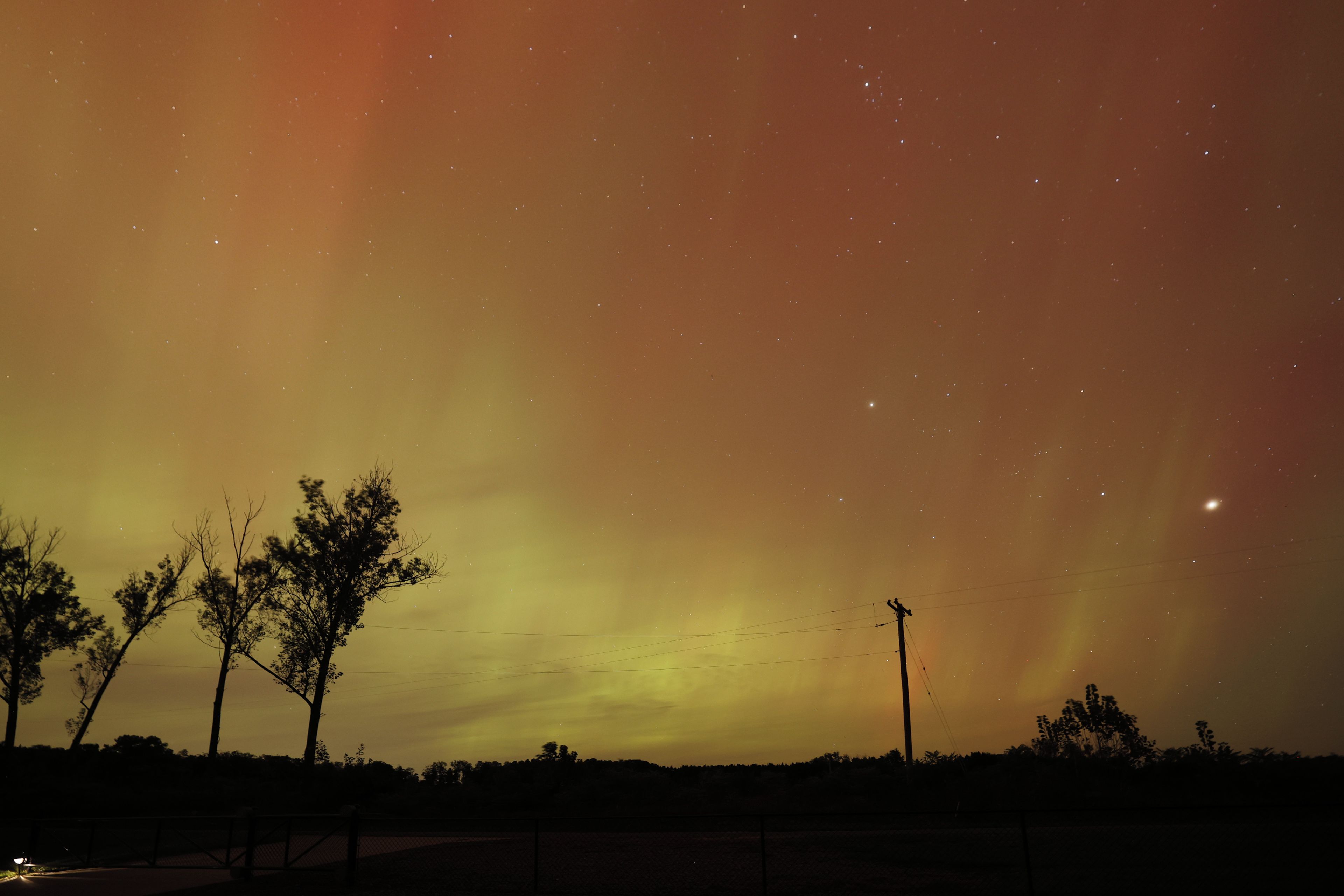 Un ciel nocturne parsemé d’étoiles et illuminé d’une faible aurore boréale.
