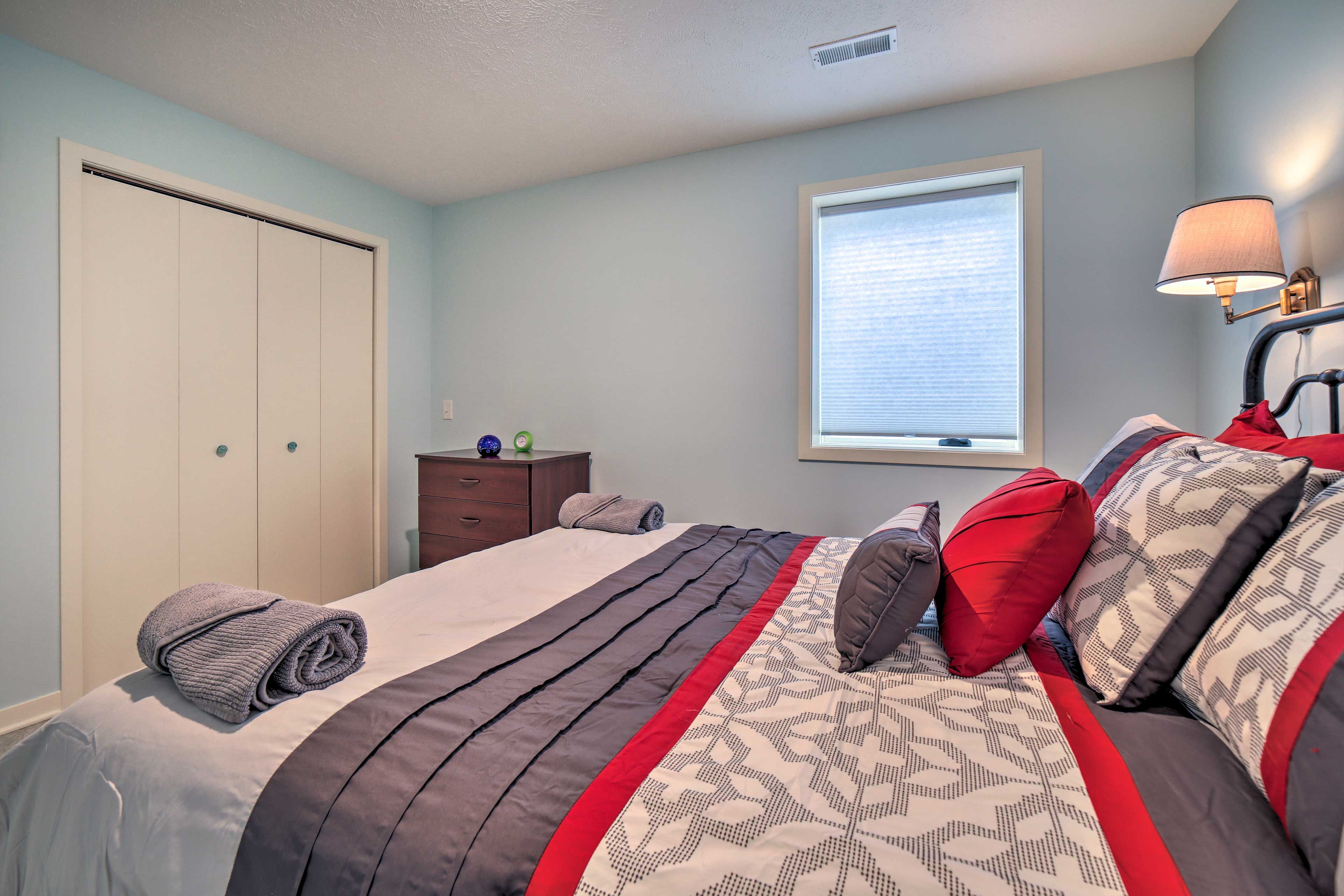 A bedroom with a bed, a window, a nightstand, and a wardrobe.