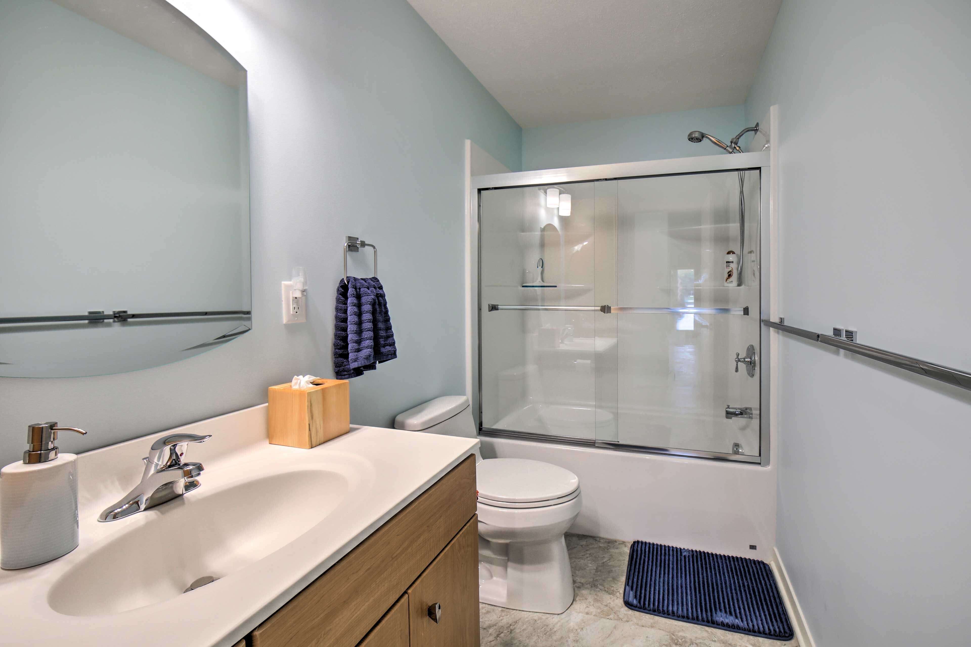 A bathroom with a white sink, a mirror, a toilet, and a glass-enclosed shower.