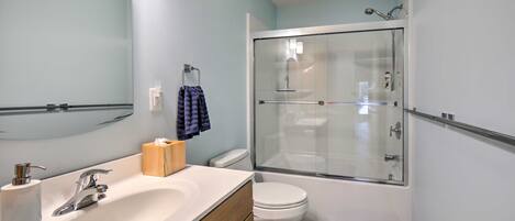 A bathroom with a white sink, a mirror, a toilet, and a glass-enclosed shower.