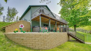 Una casa de dos pisos con un porche cubierto y un muro de contención de ladrillo.