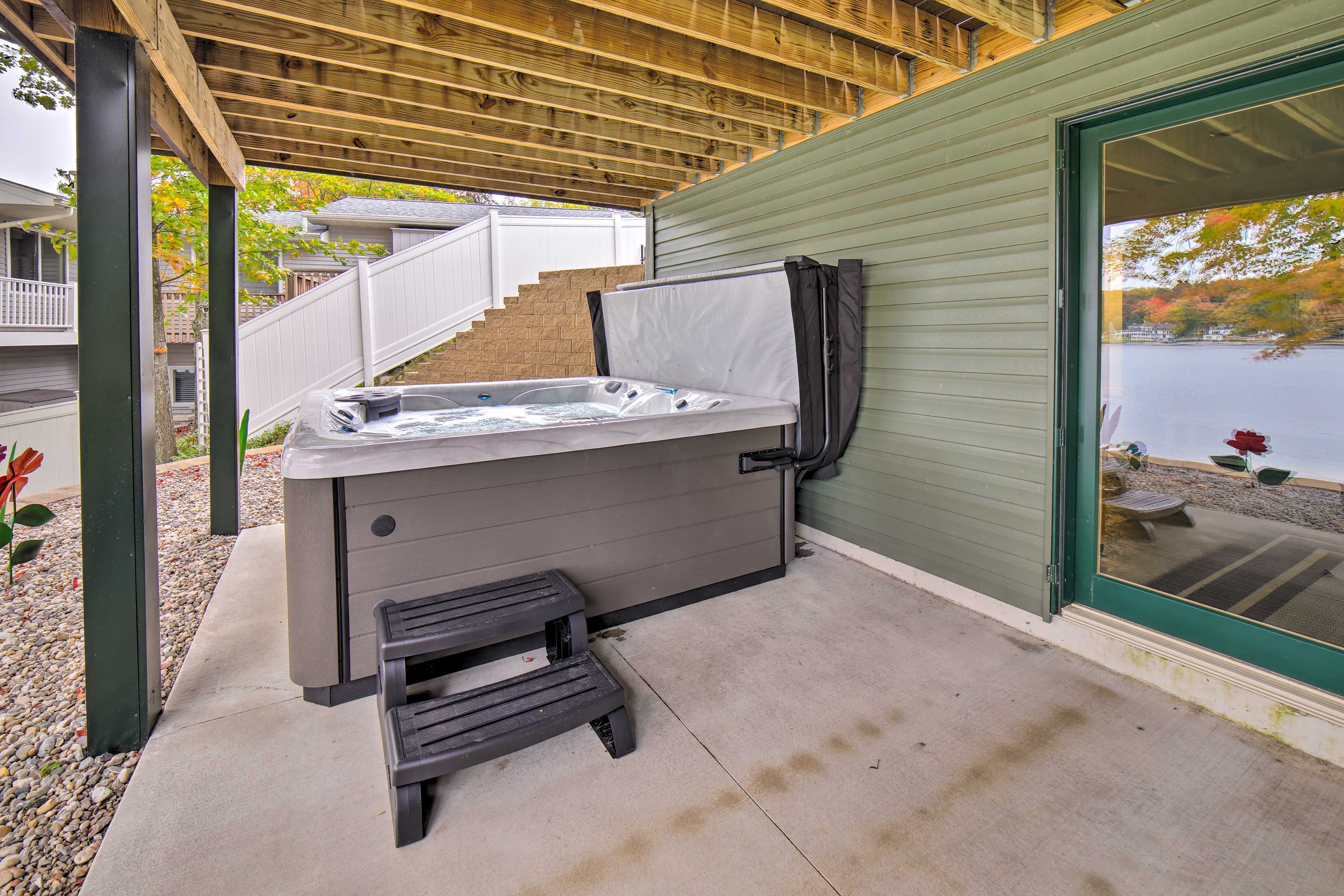 Ein Whirlpool unter einer Holzpergola mit Blick auf einen See.