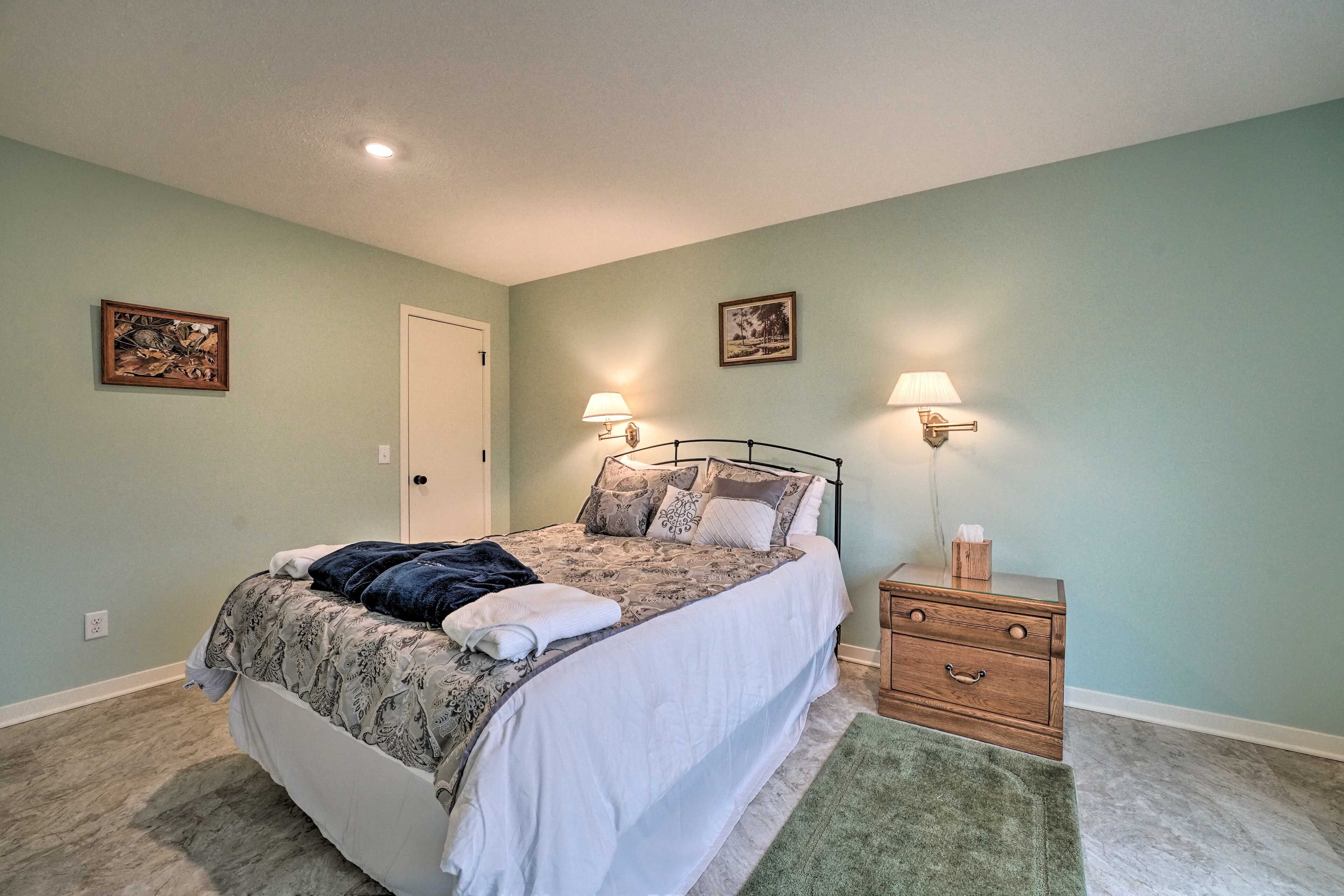 A bedroom with a bed, bedside tables, and wall-mounted lamps.