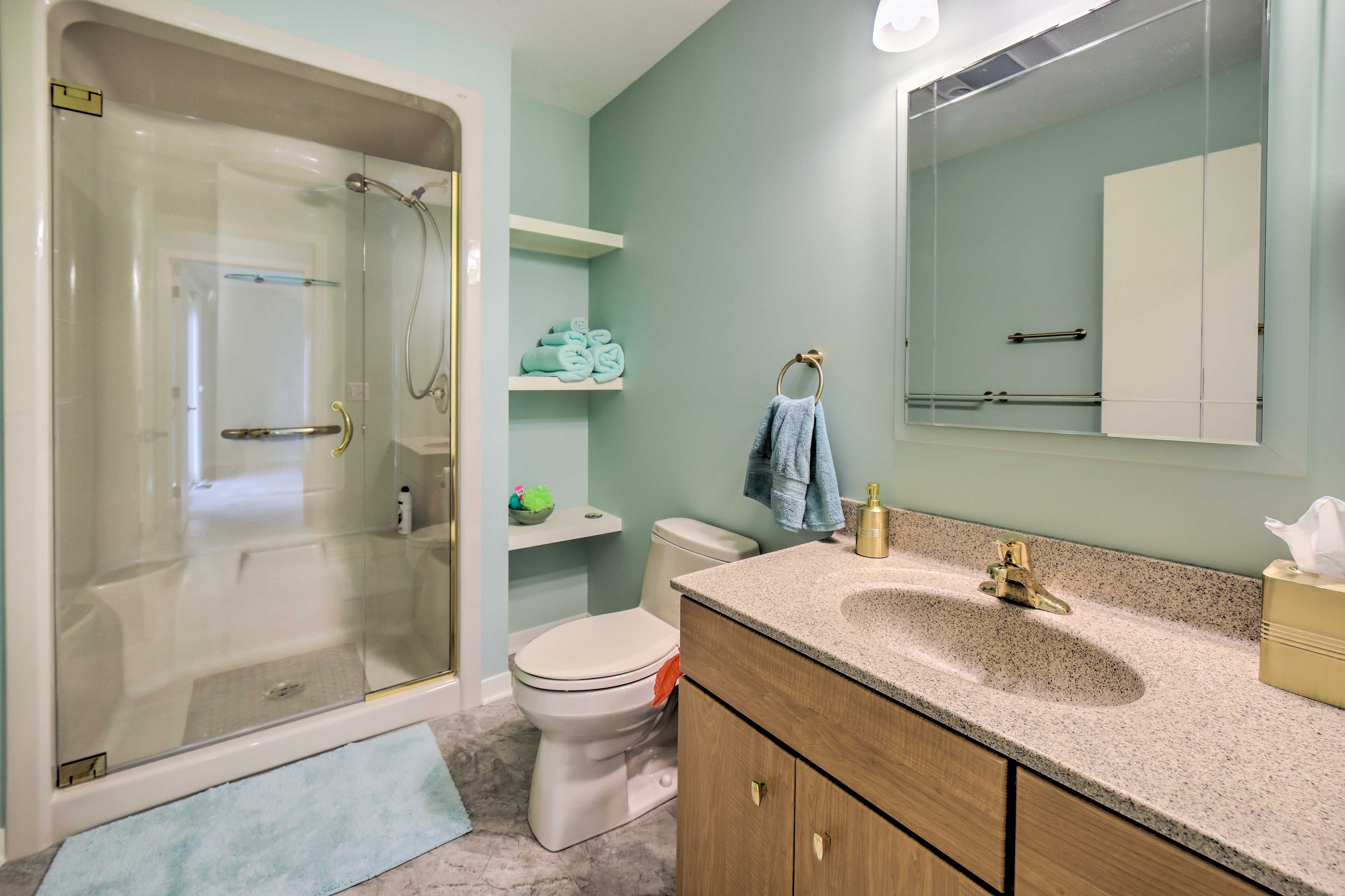 A bathroom with a glass-enclosed shower, a toilet, a sink with a vanity, and a mirror.
