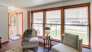 Un'ampia stanza con grandi finestre, una porta con pannello di vetro decorativo e due poltrone.