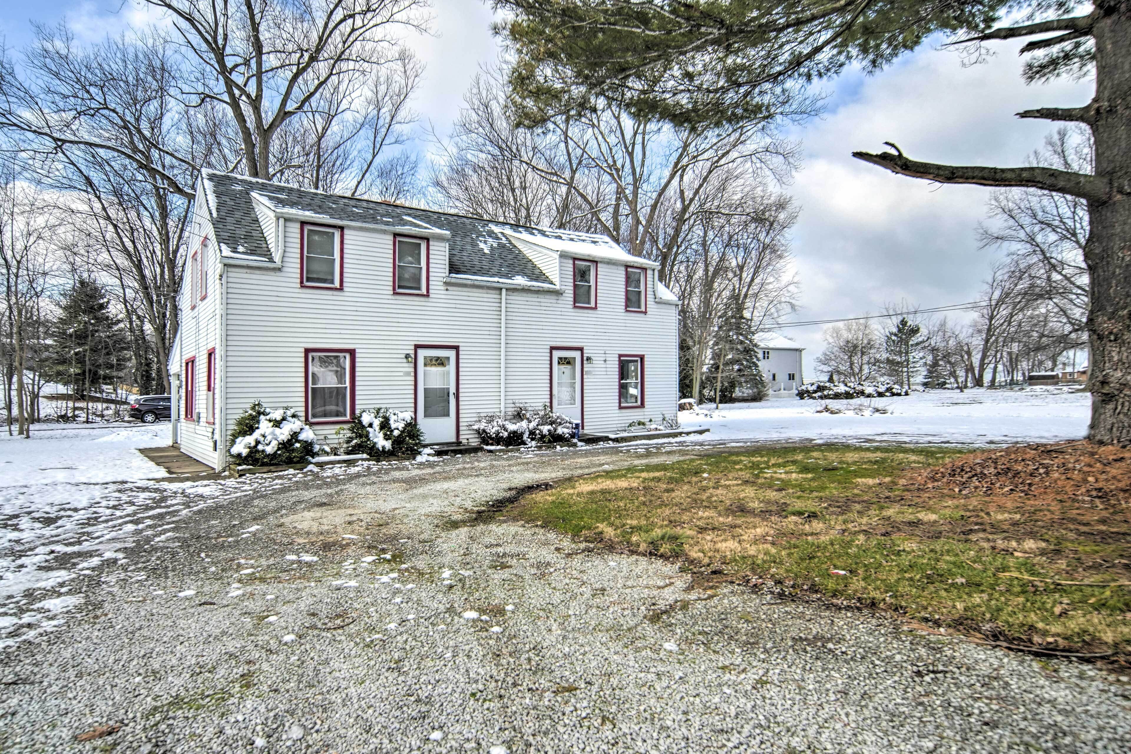A two-story house with a gravel driveway and snow on the ground.