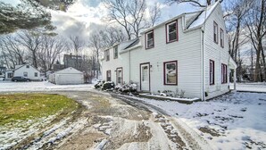 A two-story white house with red trim, a gravel driveway, and snow on the ground. - Eastlake Home w/ Patio < 1 Mi to Lake Erie! (Eastlake)