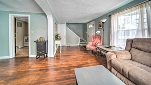 A spacious living room with hardwood flooring, a beige sofa, a pink chair, and a staircase leading to another level. - Eastlake Home w/ Patio < 1 Mi to Lake Erie! (Eastlake)