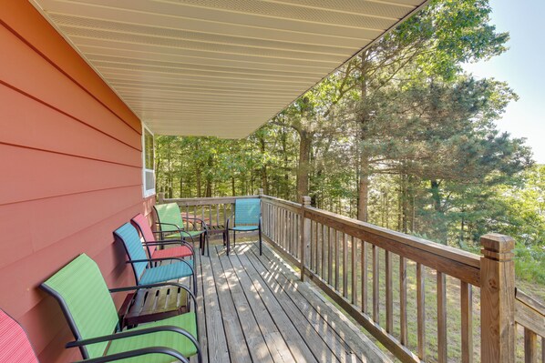 A wooden deck with chairs and a covered area, surrounded by trees. - Eagle River Apartment w/ Private Dock & Fire Pit! (Eagle River)