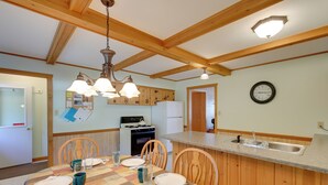 Una cocina con armarios de madera, una mesa de comedor para cuatro personas y una isla con fregadero.