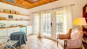 Une pièce chaleureuse avec un plafond en bois, une table à manger recouverte d’une nappe, une chaise, un canapé et une lampe.