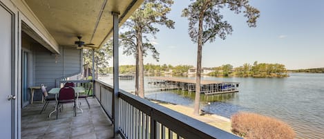 A balcony with a view of a lake, a dock, and trees.