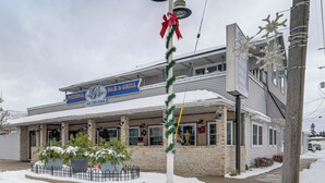 A building with a sign reading "PIZZERIA & BAR GRILL" and a Christmas decoration. - Downtown East Tawas Apt w/ Lake Huron Views (East Tawas)