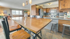 A spacious kitchen with wooden cabinets, a large island, and modern appliances. - Downtown East Tawas Apt w/ Lake Huron Views (East Tawas)